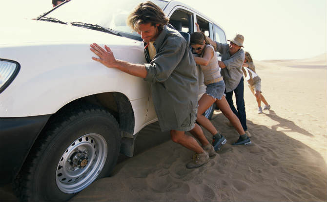 אנשים דוחפים רכב שטח בחול