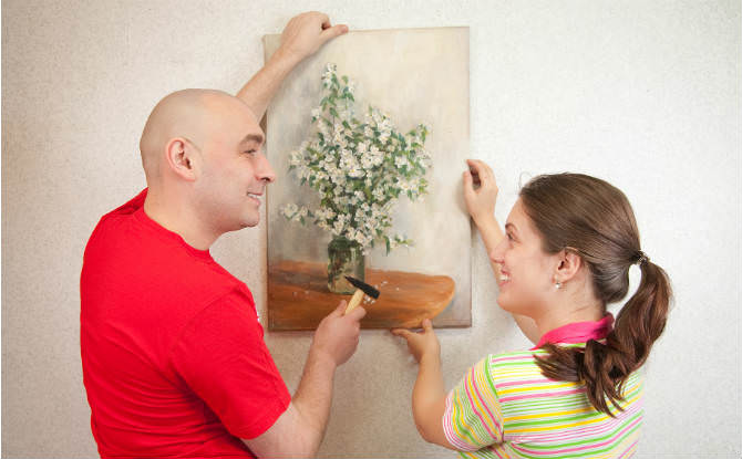 זוג תולה תמונת קנבס על הקיר
