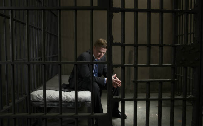 איש מעונב יושב על מיטה בכלא