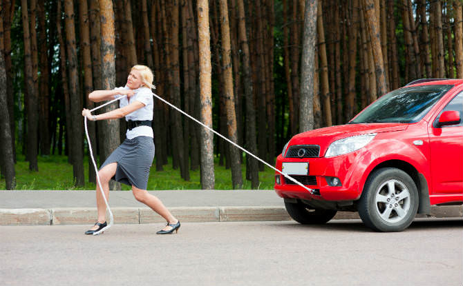אישה גוררת רכב אדום עם חבל